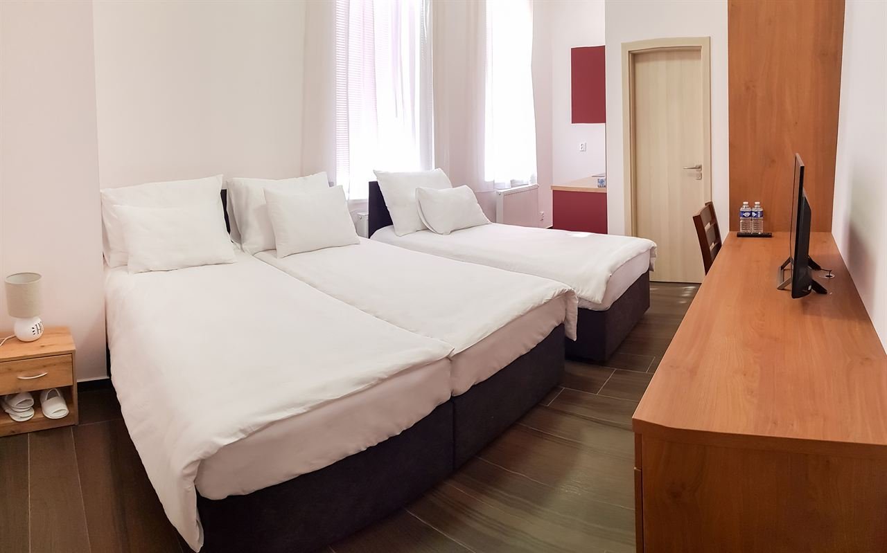 Třílůžkový pokoj se třemi lůžky vedle sebe a televizí